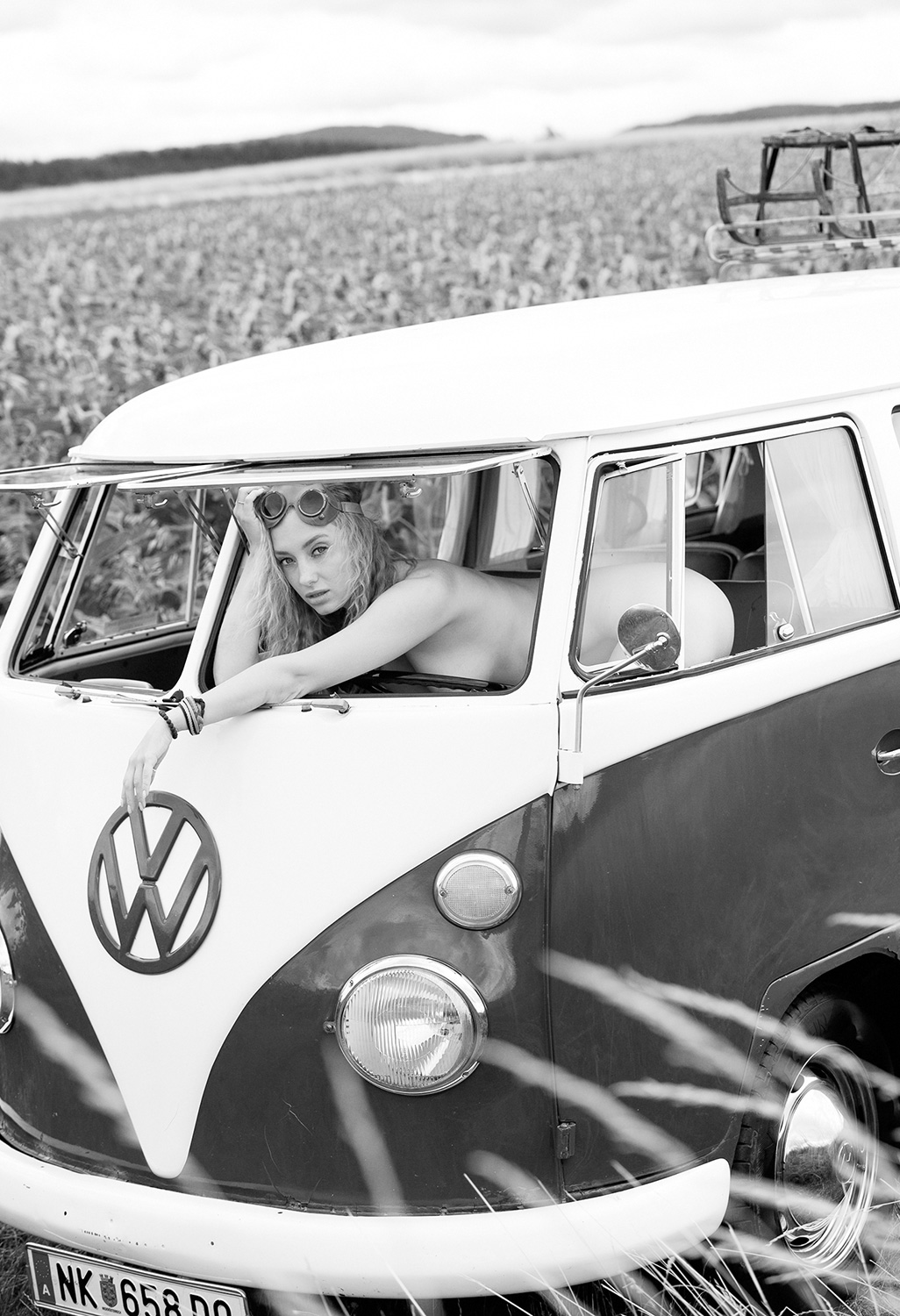 Eine Frau lehnt aus einem VW-Bus, mit verträumtem Blick und einem Hauch von Retro-Charme. Die Szene strahlt Freiheit und Nostalgie aus