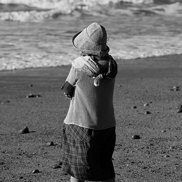 Künstlerische Streetphotography einer älteren Frau am Meer, in Gedanken versunken.