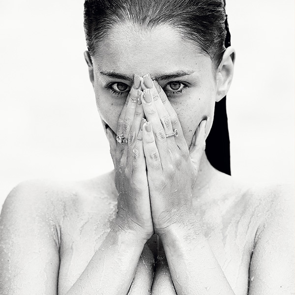 Erotische Schwarzweiß-Fotografie einer nassen Frau mit intensivem Blick, verdecktem Gesicht und sichtbarem Oberkörper – limitierte fine art aktfotografie