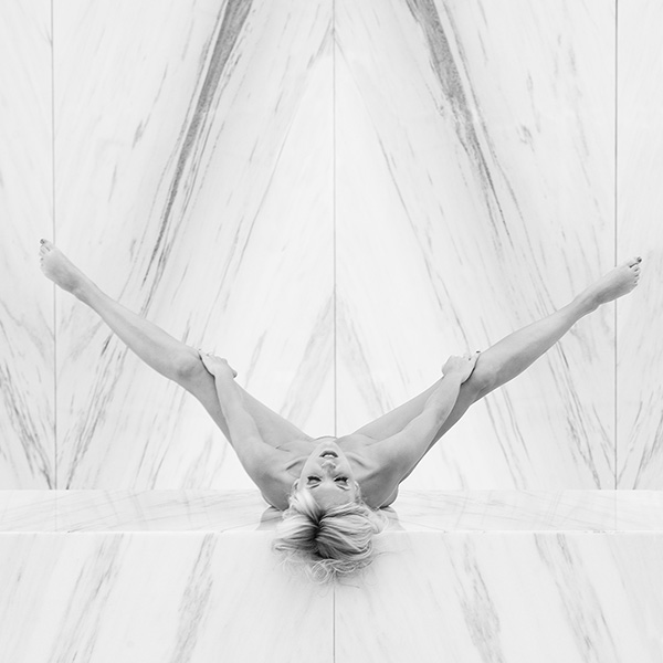 Person liegt symmetrisch auf dem Rücken in einem Innenraum, zentral im Bild positioniert – limitierte Fine Art Aktfotografie